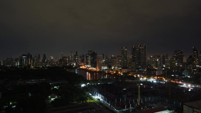 Night timelapse of Bangkok city light panorama from a high point. Queen Sirikit National Convention Centre construction site near Benjakitti Park and Lake, Millenium Residence Apartment, CTI Tower 