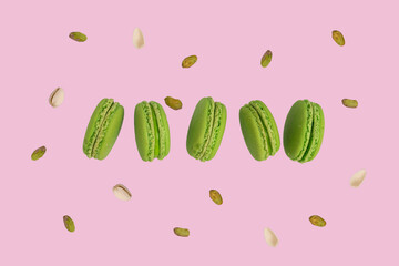 A row of green macaroons or French macarons floating on soft pink background.