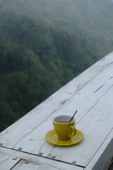 cup of coffee on table with hill on background