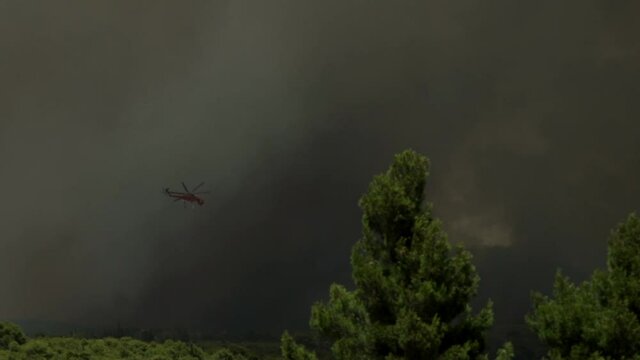 Big fire at Varimbombi, Athens, Greece, August 03, 2021. Ericsson firefight helicopter attempts through huge black smoke 120 fps