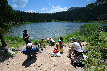 Hikers enjoy view of Hassell Lake in Arapaho National Forest, Colorado on sunny summer afternoon.