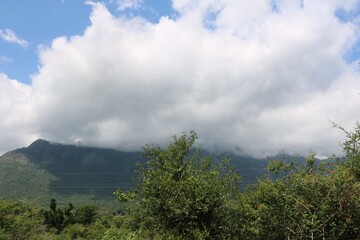 white clouds blue sky green trees hills