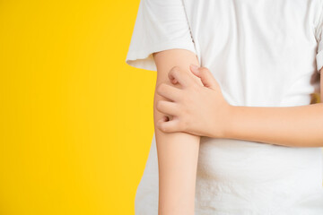 Little Asian girl has allergies with mosquitoes bite, girl scratching her arm with red spot.