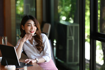 Fototapeta premium Thoughtful businesswoman sitting in modern office and looking out of window.
