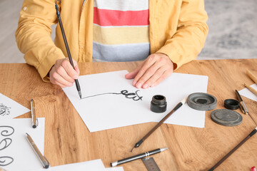 Young male calligrapher working at home, closeup