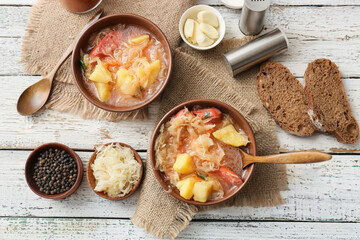 Composition with tasty sauerkraut soup on light wooden background