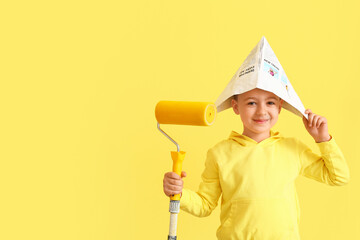 Little boy with paint roller on color background