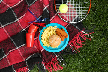Fast food with tennis racket on plaid in park