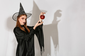 Beautiful woman dressed as witch for Halloween on light background