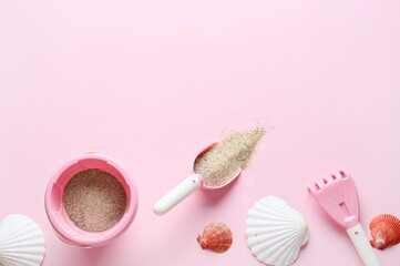 Set of beach accessories for children, sand and seashells on color background
