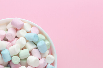 Fototapeta na wymiar Colorful marshmallows in a bowl with empty space on pink background