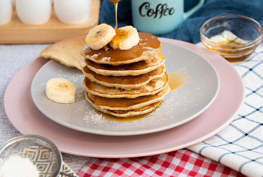 Pour maple syrup over homemade banana cupcakes. A slide of hot cupcakes with fresh bananas on a plate. Maple serop sprouts over cupcakes. Portion of breakfast on a plate. High quality photo