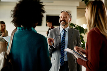 Happy mature teacher communicates with students in hallway at the university.