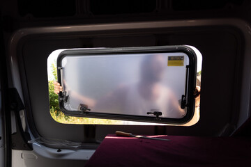Inside a camper van - man installing a side window 