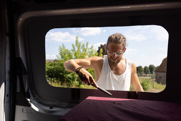 Man using a file to deburr a window opening in a camper van