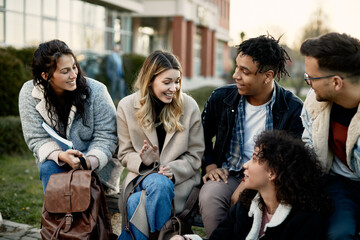 Group of happy multi-ethnic university friends have fun while talking outdoors at campus.