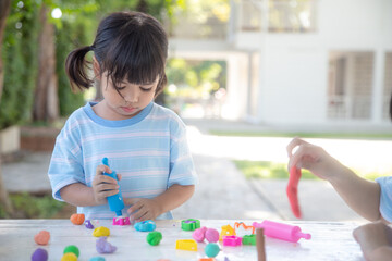 Asian kids play with clay molding shapes, learning through play