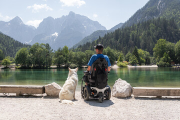 Disabled man on wheelchair with his dog on a trip in nature.