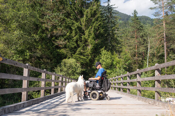 Disabled man on wheelchair with his dog on a trip in nature.