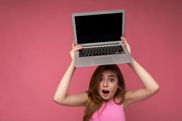 Naklejka premium Close-up portrait of Beautiful amazed young woman saying wow with open mouth holding netbook computer looking at camera