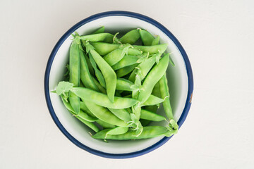 Sugar snaps in white enamel bowl on a table