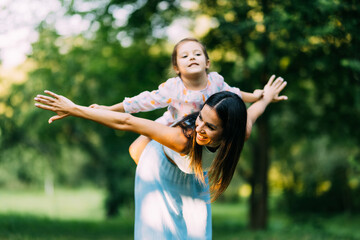 Young daughter on a piggy back ride with her mother.
