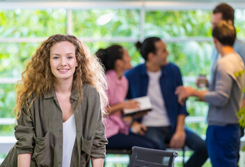 Focus foreground smart trendy hipster beautiful casual female leader standing in startup creative modern company, smiling with profession, happiness, confidence and blur background diverse colleagues.