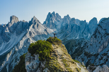 Aerial view of a woman hiker raising her hands on mountain top enjoying Cadini di Misurina mountain peaks, Italian Alps, Dolomites, Italy, Europe