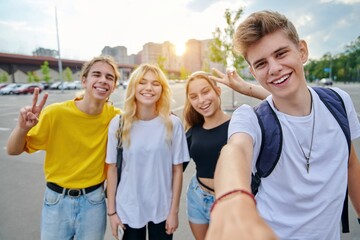 Smiling group of teenagers taking selfie, happy four teens looking at camera