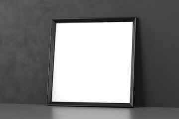 Blank wooden picture frame leaning over dark wall