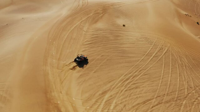 Dune buggy all terrain vehicle driving through arid desert near Dubai, aerial