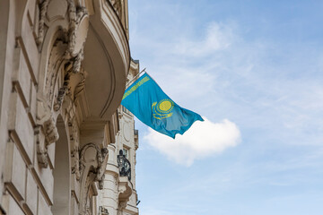 Kazakhstan flag agains blue sky. Kazakhstan flag hanging on a pole in front of the house. National flag waving on a home displaying on a pole on a front door of a building.