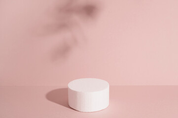Sandy podium with stone for cosmetic product against pastel background.