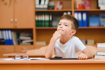 Little child writing with colorful pencils, indoors. Elementary school and education. Kid learning writing letters and numbers.