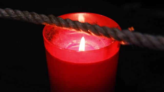 Burning a jute rope on the fire of a candle for the shibari ritual.