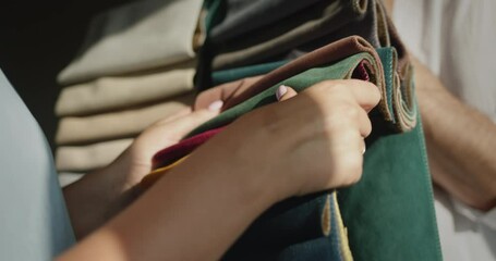 The buyer chooses the fabric in the textile store, the seller holds samples with multi-colored fabric