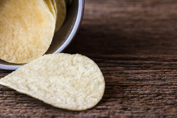 Potato slice chips crisps in paper tube box on wooden planks.