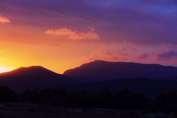 Colorful sunset in shades of pink, purple and orange over the low mountains in Primorsky Krai, Russia. Contrasting defocused background with the silhouette of the mountains