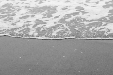Sea waves, sea water on the sand. The atmosphere of the sea and relaxation. Empty beach. Yellow sand. Sea view. Poster. Postcard. Black and white photography. Vertical photography of nature.