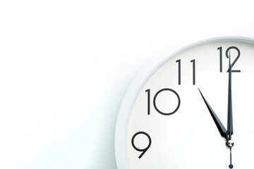 A wall clock that announces 11 o'clock on the hour