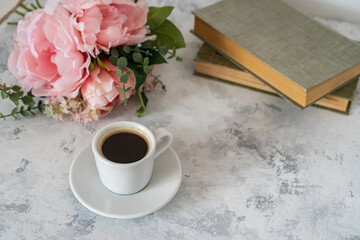 there is a laptop and a mug of coffee on the table, next to it lies a bouquet of flowers and magazines