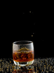 splash in glass with whiskey with ice on black background