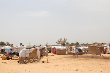 Refugee camp made of local materials and plastic sheeting, people living in very poor conditions, lack of clean water, access to health