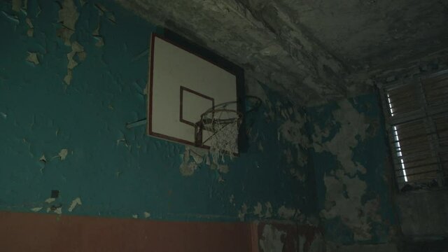 Basketball hoop with a net in the beam of a flashlight in an old abandoned and dilapidated gym
