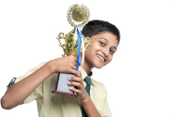Clever schoolboy raising his trophy as a winner in school competition.