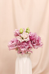 Bouquet of eustoma flowers in vase in front of beige cloth background. Present for 8 March, Mothers Day. Springtime composition with copyspace.