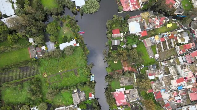 Jib down above canal in Xochimilco, Mexico City. We can see reflections of clouds in water