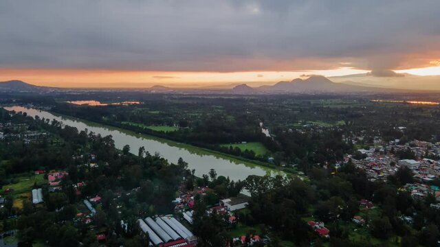 Hyperlapse in fixed heading to right, above Xochimilco at a morning cloudy, during sunrise. Can see canals an reflections in water