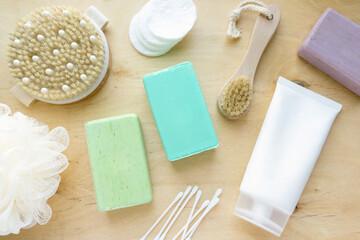 Flat lay of bath and hygiene products. Soap, shampoo and massage brushes on wooden background, top view