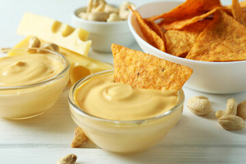 Snacks with cheese sauce on white wooden table